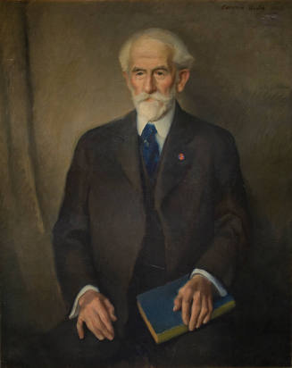 Portrait of an older man in a dark suit holding a blue book on his lap