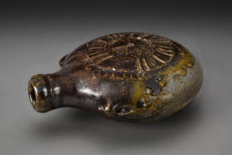 Round ceramic bottle with a textured sunburst design on top and dark brown glaze.